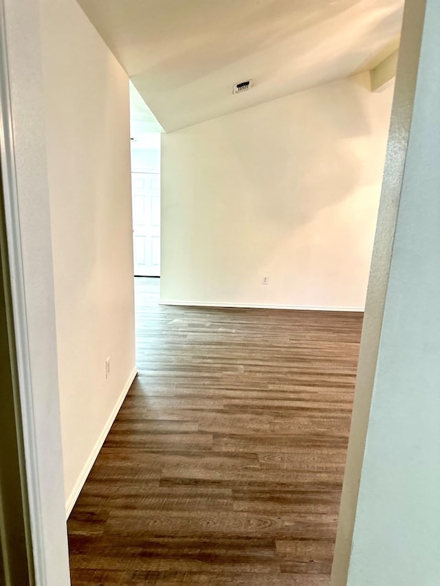 unfurnished room featuring dark wood-type flooring and lofted ceiling