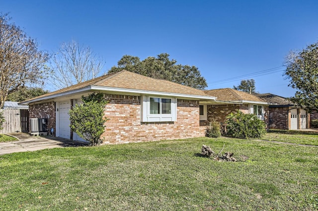 ranch-style home featuring a garage, a front lawn, and central air condition unit