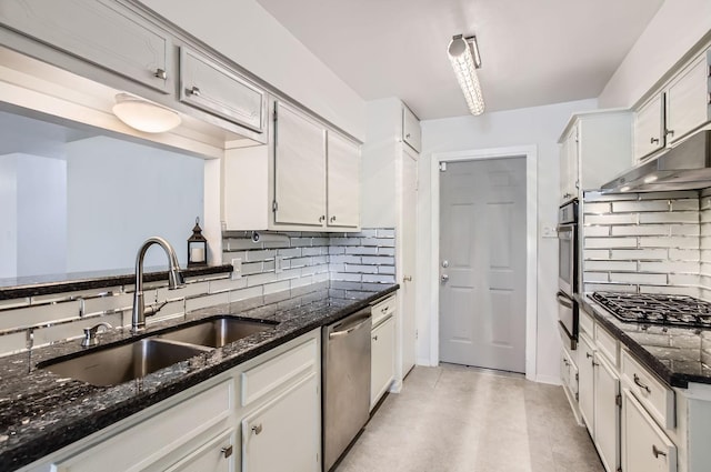 kitchen featuring white cabinets, appliances with stainless steel finishes, dark stone countertops, and sink