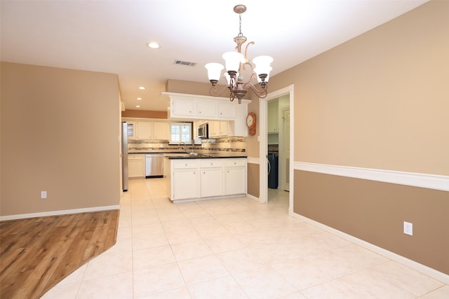 kitchen featuring appliances with stainless steel finishes, tasteful backsplash, decorative light fixtures, a notable chandelier, and white cabinets