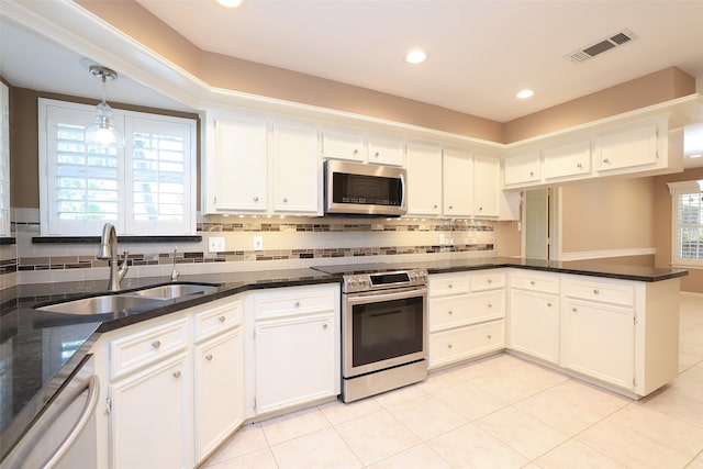 kitchen featuring sink, kitchen peninsula, appliances with stainless steel finishes, decorative light fixtures, and white cabinetry