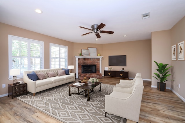 living room with ceiling fan, a fireplace, and light wood-type flooring