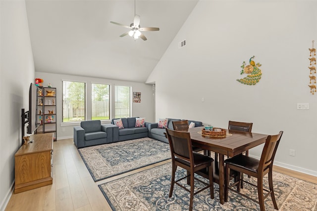 dining room with light hardwood / wood-style floors, high vaulted ceiling, and ceiling fan