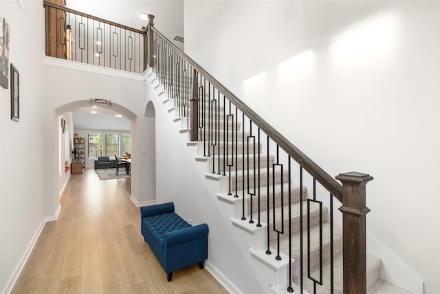 stairway with a high ceiling and wood-type flooring