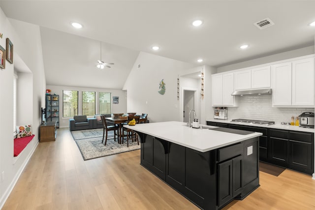 kitchen featuring ceiling fan, sink, stainless steel gas cooktop, a center island with sink, and light hardwood / wood-style flooring