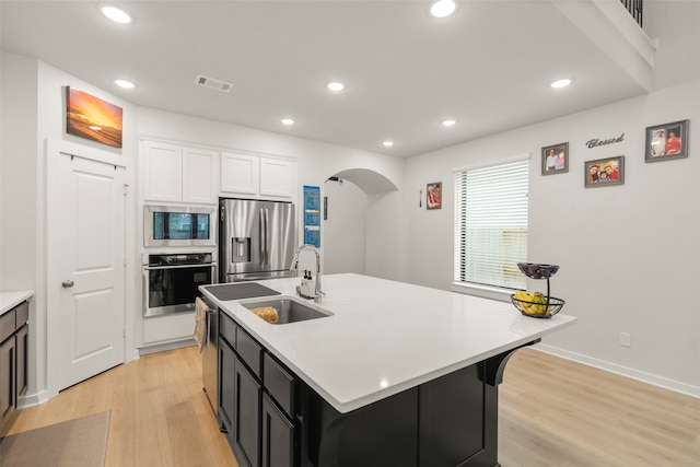 kitchen featuring a kitchen island with sink, appliances with stainless steel finishes, light wood-type flooring, and sink