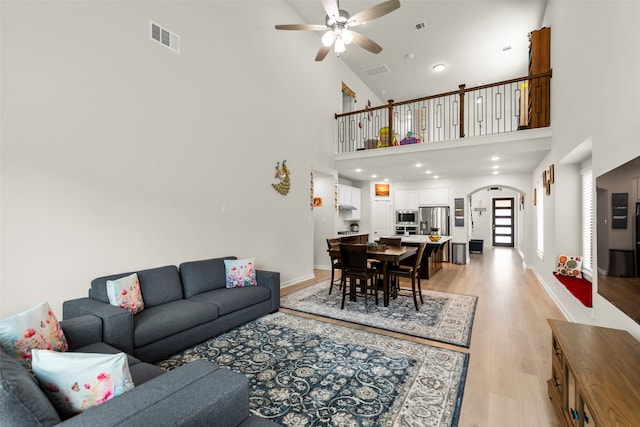 living room featuring light wood-type flooring, high vaulted ceiling, and ceiling fan