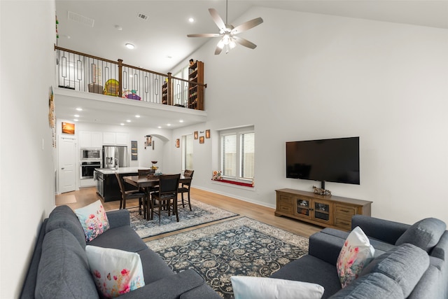 living room featuring high vaulted ceiling, light wood-type flooring, and ceiling fan