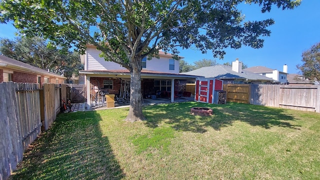 back of house with a lawn, a patio area, a shed, and a fire pit