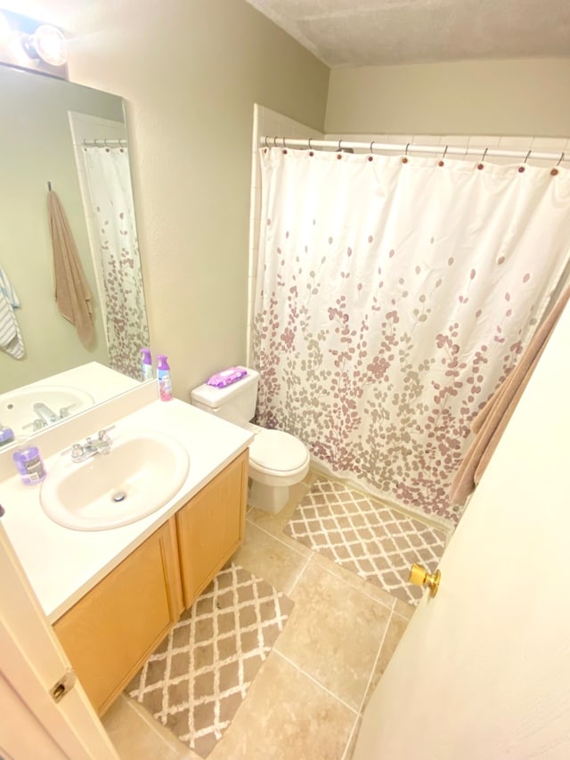 bathroom featuring tile patterned flooring, vanity, toilet, and a textured ceiling