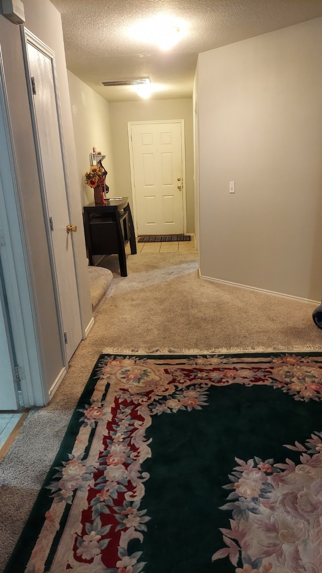 hall with a textured ceiling and light carpet