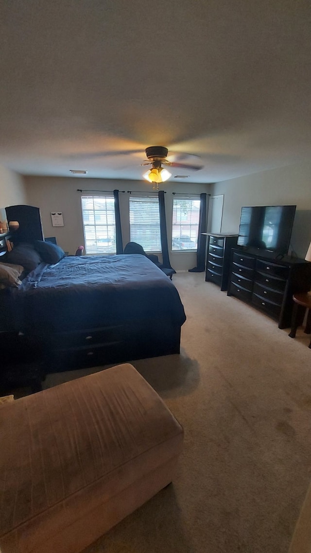 carpeted bedroom with multiple windows and ceiling fan