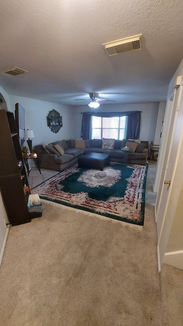 living room featuring carpet, ceiling fan, and a textured ceiling