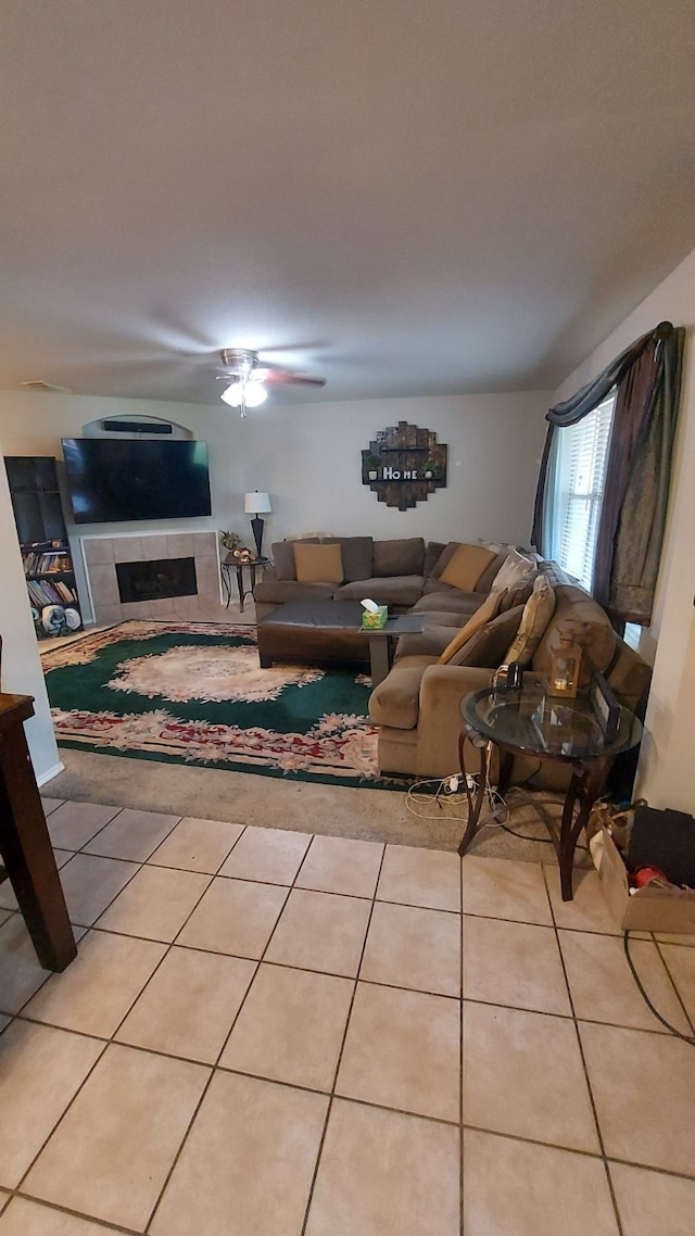 tiled living room featuring ceiling fan and a fireplace