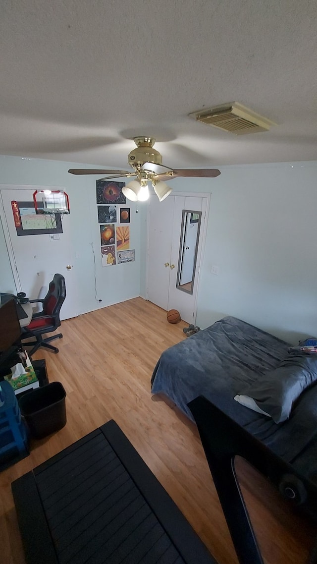 bedroom featuring hardwood / wood-style flooring, ceiling fan, and a textured ceiling