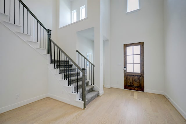 entryway featuring a towering ceiling and light hardwood / wood-style floors