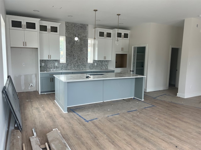 kitchen featuring a center island with sink, pendant lighting, and white cabinets