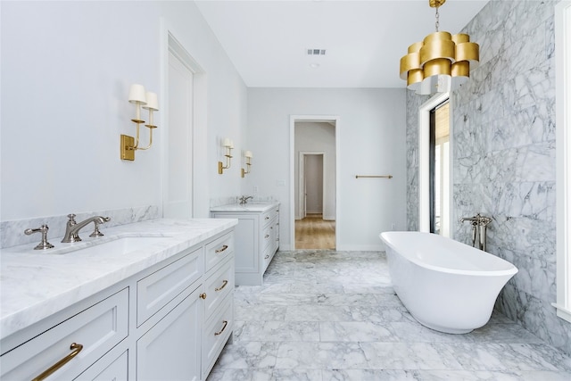 bathroom with a tub, vanity, and tile walls