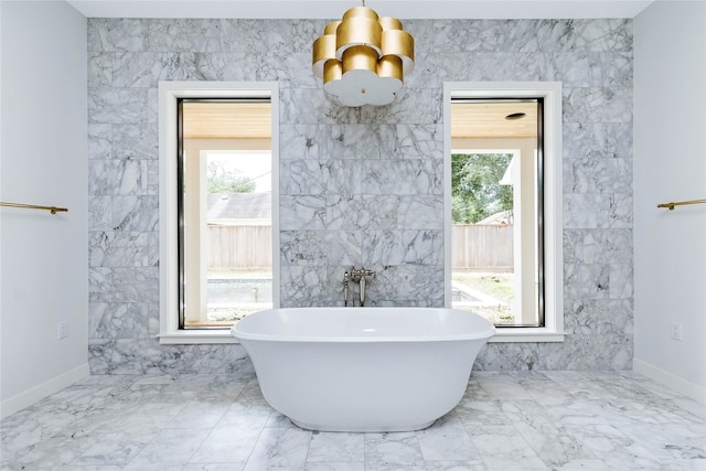 bathroom with a bathtub, a wealth of natural light, and tile walls