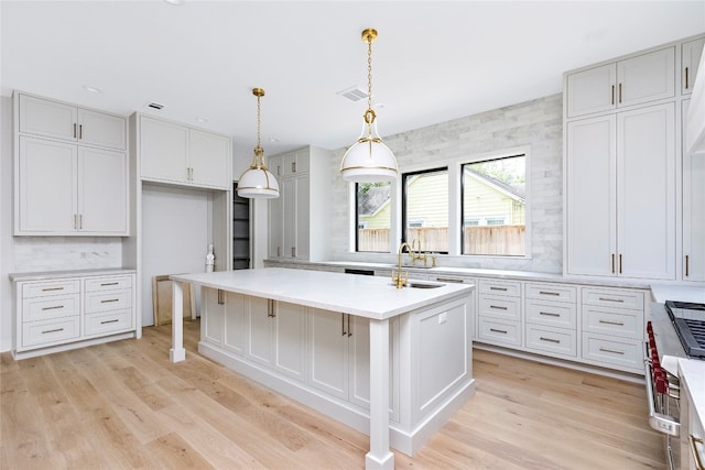 kitchen featuring pendant lighting, light hardwood / wood-style flooring, an island with sink, and sink