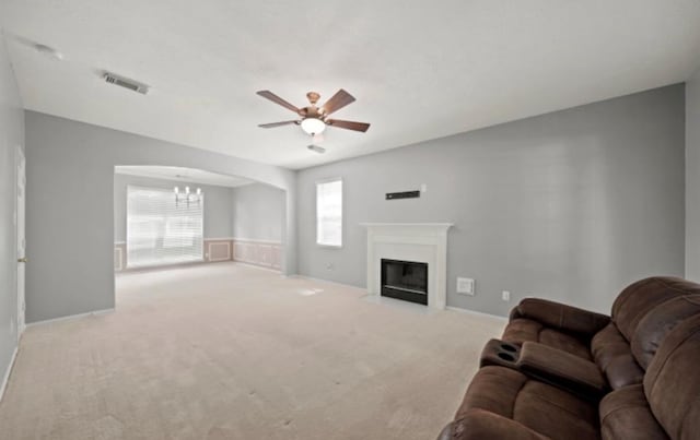 carpeted living room featuring ceiling fan with notable chandelier