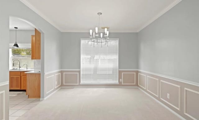 unfurnished dining area featuring sink, crown molding, a notable chandelier, and light colored carpet