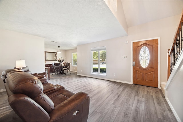 living room with light wood-type flooring, a textured ceiling, and a chandelier