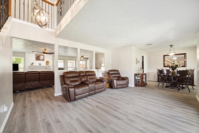 living room with light hardwood / wood-style floors and ceiling fan with notable chandelier