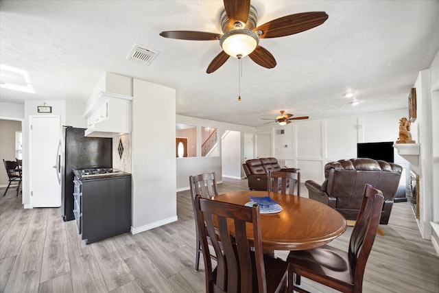 dining area featuring a textured ceiling, light hardwood / wood-style floors, and ceiling fan