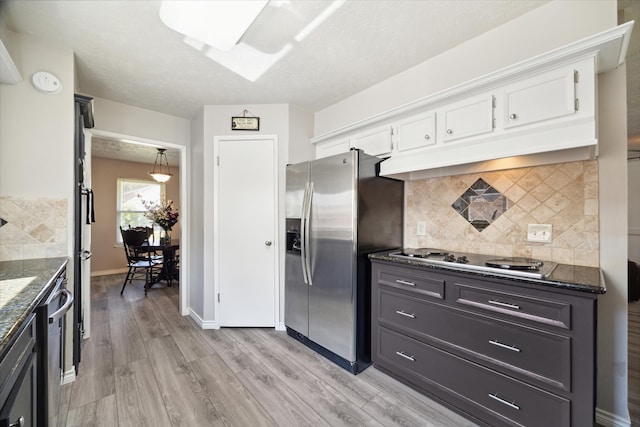 kitchen featuring pendant lighting, backsplash, appliances with stainless steel finishes, light hardwood / wood-style floors, and white cabinetry