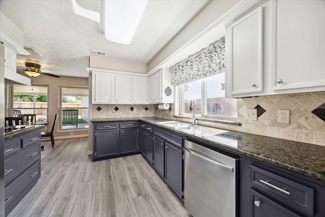 kitchen with ceiling fan, dark stone countertops, light wood-type flooring, white cabinetry, and stainless steel appliances