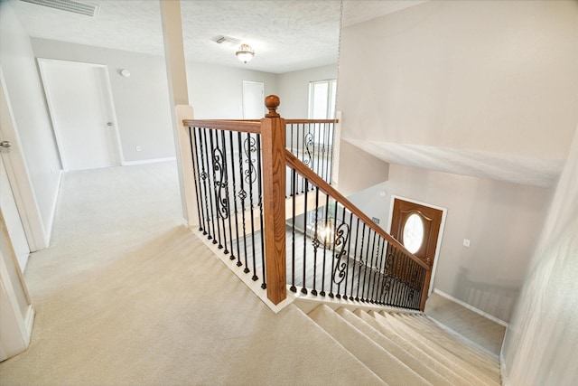 staircase featuring carpet, a textured ceiling, and a healthy amount of sunlight