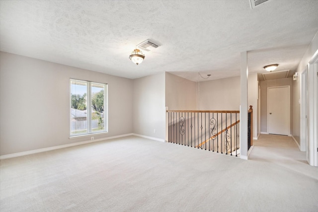 unfurnished room with light colored carpet and a textured ceiling