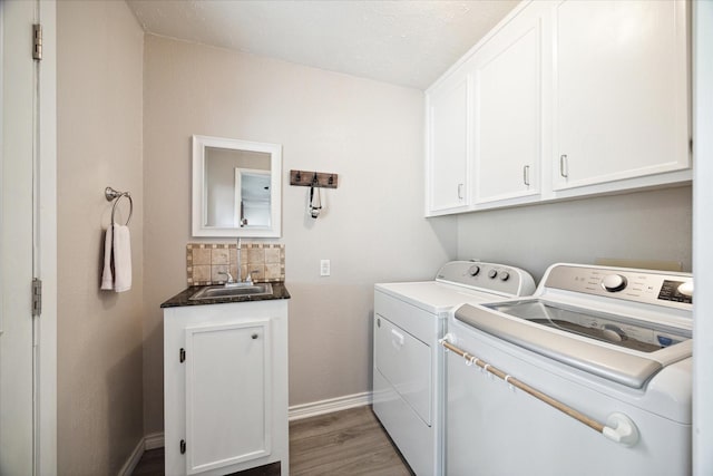 laundry room with hardwood / wood-style flooring, washer and clothes dryer, cabinets, and sink