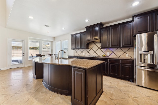 kitchen with a kitchen island with sink, stainless steel appliances, sink, dark brown cabinetry, and decorative light fixtures