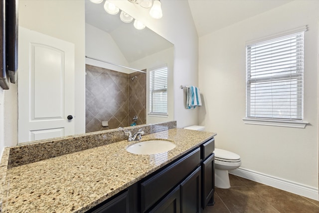 bathroom with a tile shower, toilet, lofted ceiling, vanity, and tile patterned flooring