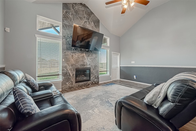 living room with hardwood / wood-style flooring, a healthy amount of sunlight, ceiling fan, and a stone fireplace