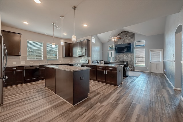 kitchen with stainless steel appliances, dark brown cabinetry, a center island, and a tile fireplace