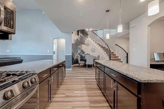 kitchen with light hardwood / wood-style flooring, dark brown cabinets, stainless steel appliances, hanging light fixtures, and a center island