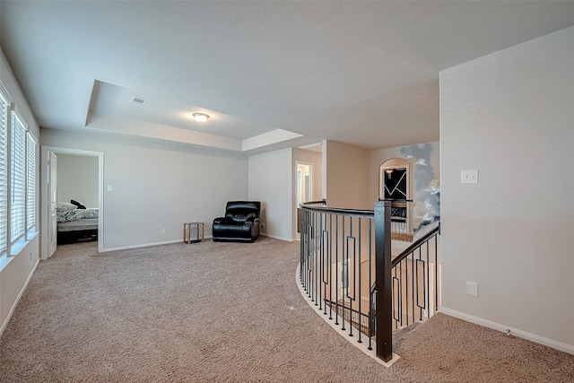 hallway with carpet floors and a raised ceiling