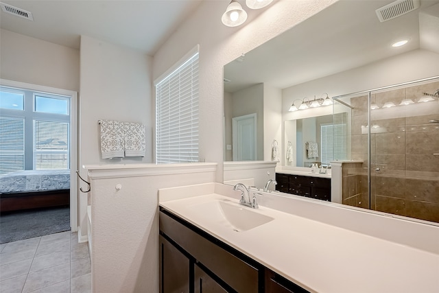 bathroom with a tile shower, tile patterned flooring, and vanity