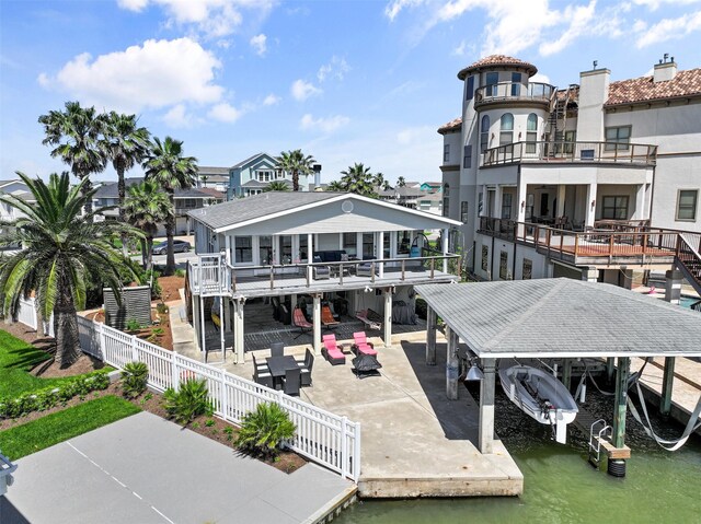 rear view of property with boat lift, a fenced backyard, a water view, and a patio area