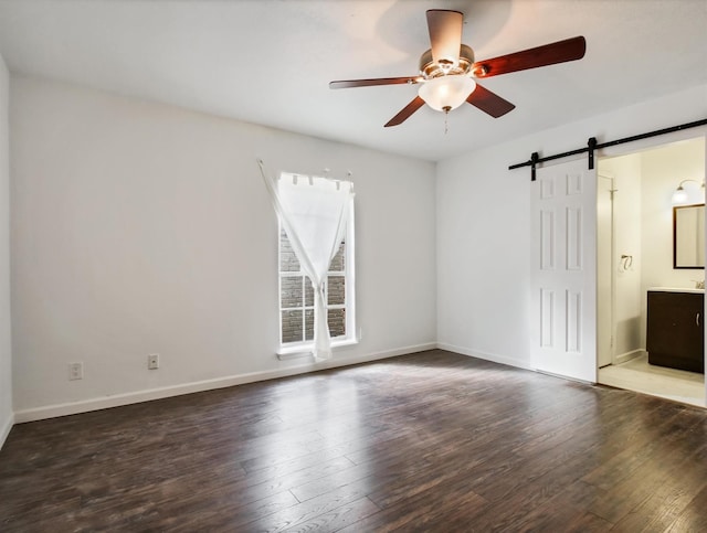 unfurnished room featuring ceiling fan, a barn door, and dark hardwood / wood-style floors