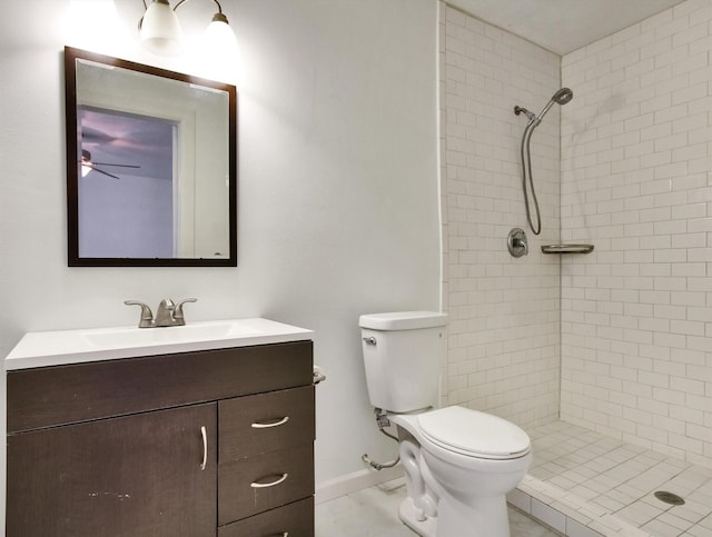 bathroom with tiled shower, tile patterned flooring, vanity, and toilet