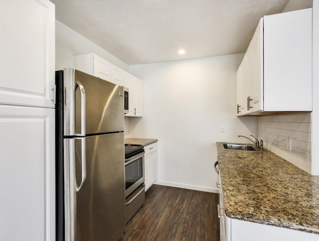 kitchen with stainless steel appliances, dark hardwood / wood-style flooring, dark stone counters, sink, and white cabinetry