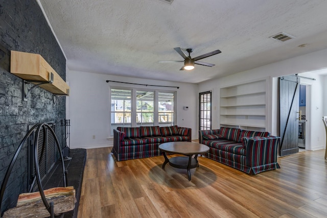 living room featuring a fireplace, hardwood / wood-style floors, ceiling fan, and built in shelves