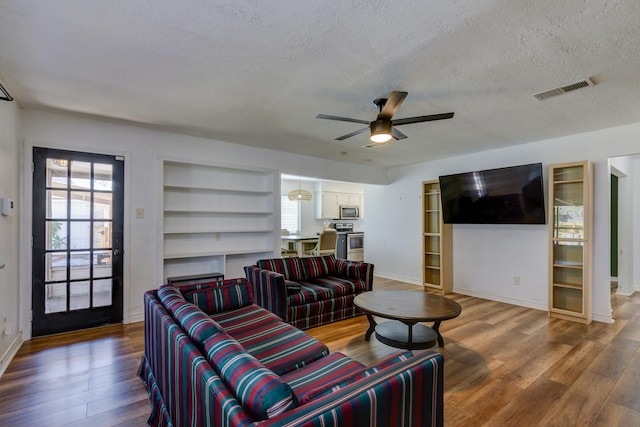 living room featuring hardwood / wood-style flooring, ceiling fan, and a textured ceiling