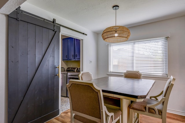 dining area featuring a barn door, washer and clothes dryer, and light hardwood / wood-style floors