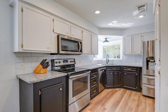 kitchen featuring light stone countertops, stainless steel appliances, white cabinetry, and sink