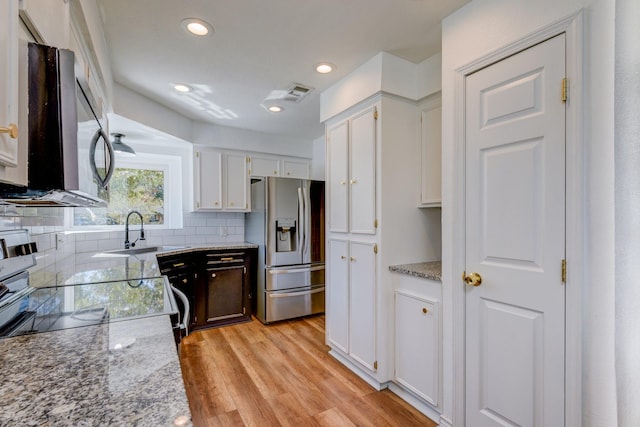 kitchen with white cabinets, light stone countertops, stainless steel fridge with ice dispenser, and sink